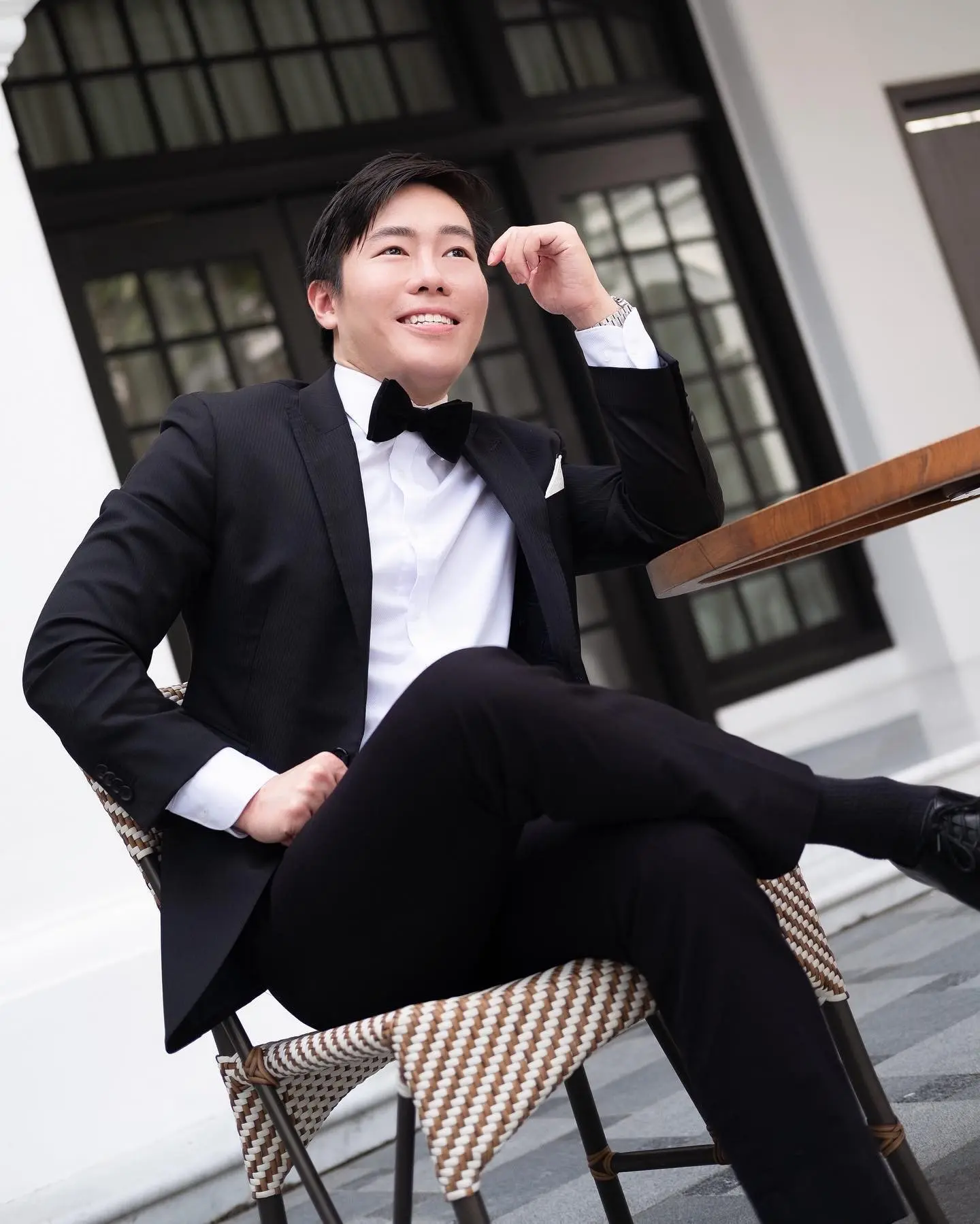 Luke Lee in black tie, seated at a café table